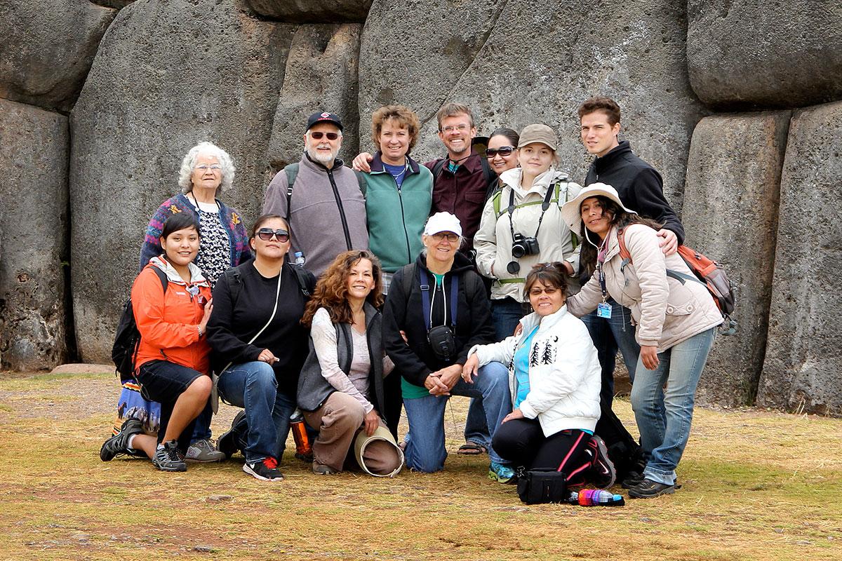 Group of 13 people standing in front of rock formation